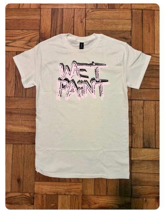 White t-shirt with 'Wet Paint' text on a wooden surface